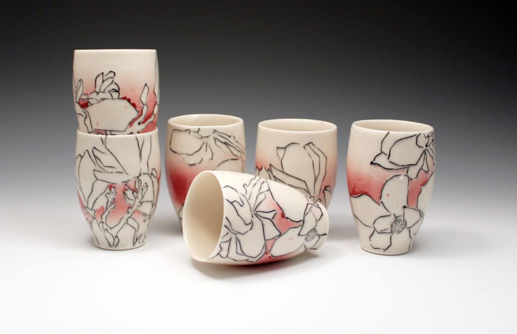 Tumblers by Nikki Navaille. White cups with black graphic drawings of magnolias and pink gradient background. 2020.